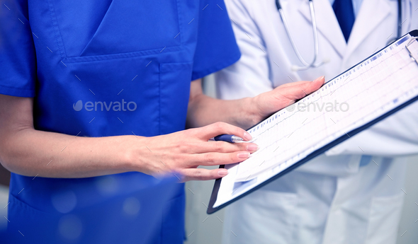 close up of doctors with clipboard at hospital