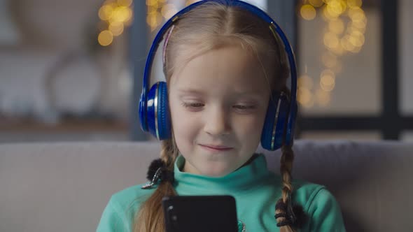 Little Girl in Headphones Enjoying Music on Phone alt