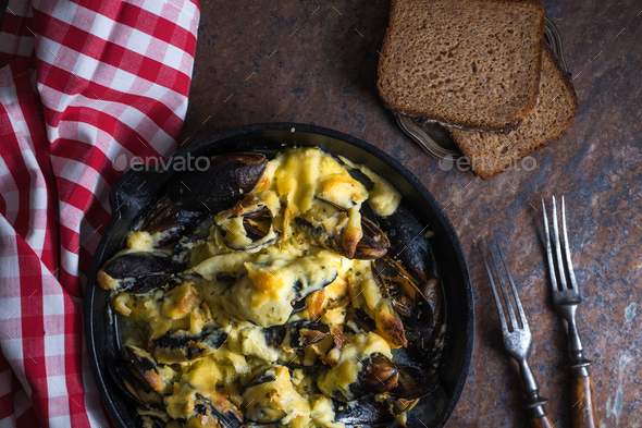Mussels with cheese sauce in a frying pan, napkin in a red cage close-up Stock Photo by Deniskarpenkov
