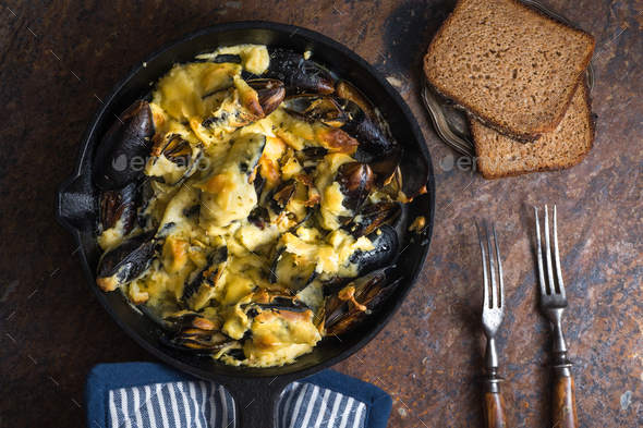 Mussels in a frying pan with cheese sauce, napkin in blue stripes Stock Photo by Deniskarpenkov