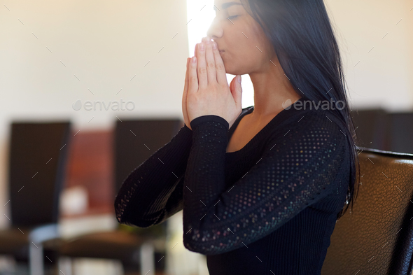close up of sad woman praying god in church