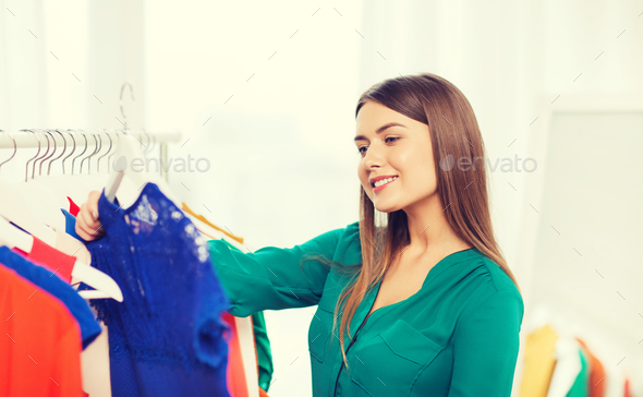 happy woman choosing clothes at home wardrobe