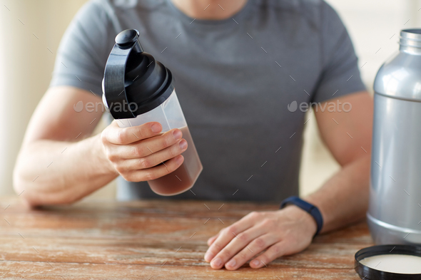 close up of man with protein shake bottle and jar - Stock Photo - Images