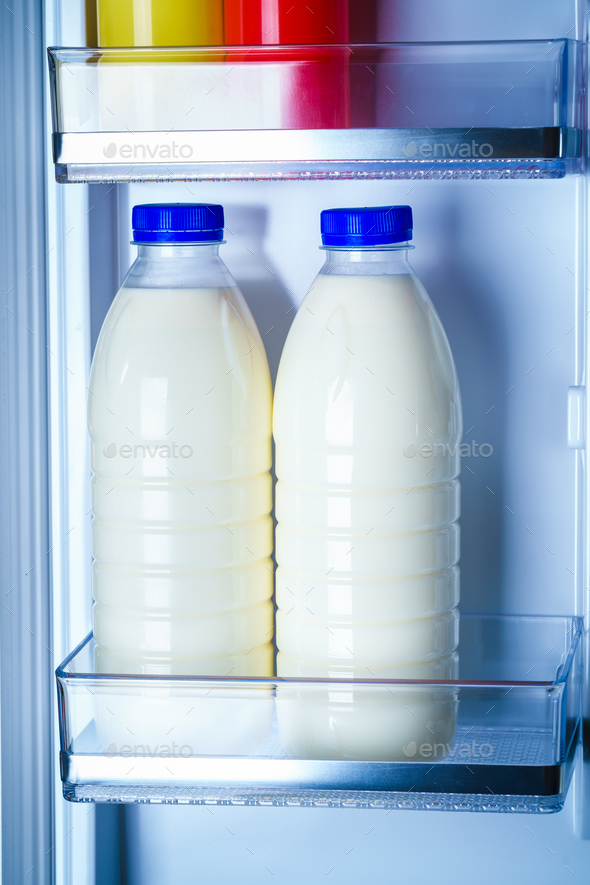 Bottles of milk in the fridge Stock Photo by cookelma PhotoDune