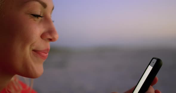 Woman using mobile phone on beach at dusk 4k