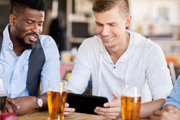 male friends with tablet pc drinking beer at bar - Stock Image - Everypixel