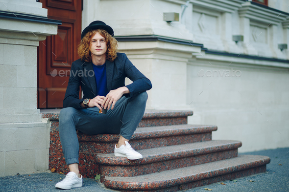Red haired hipster man sitting on stairs thinking - Stock Photo - Images