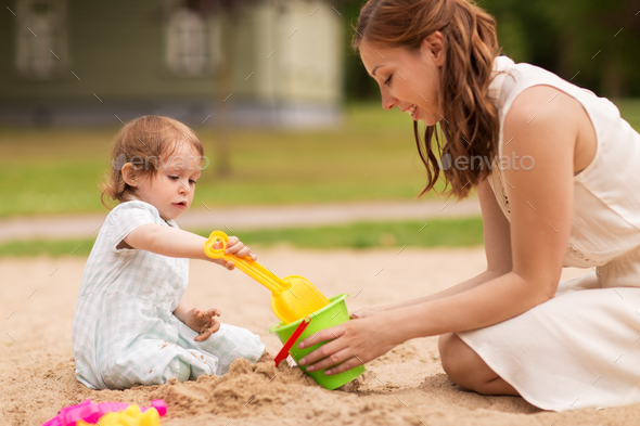 happy mother with baby girl playing in sandbox - Stock Photo - Images
