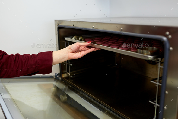 chef with macarons on oven tray at confectionery