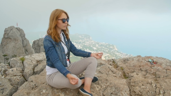 Young Beautiful Woman Meditating and Doing Yoga on Top of the Mountains