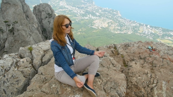 Young Beautiful Woman Meditating and Doing Yoga on Top of the Mountains