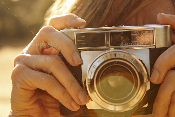 Woman taking pictures with vintage camera. Back light. Travel background.