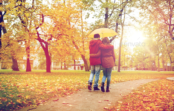 happy couple with umbrella walking in autumn park