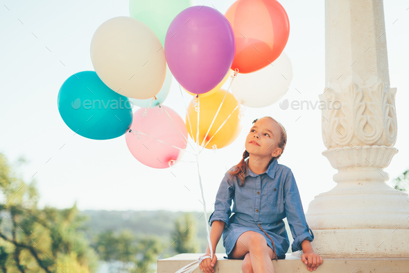 Cute girl portrait holding colorful balloons in the city park