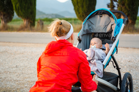 Mother with stroller enjoying motherhood at sunset landscape