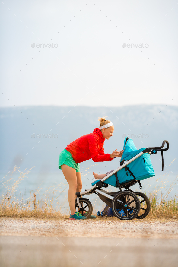Mother with stroller enjoying motherhood at sunset landscape