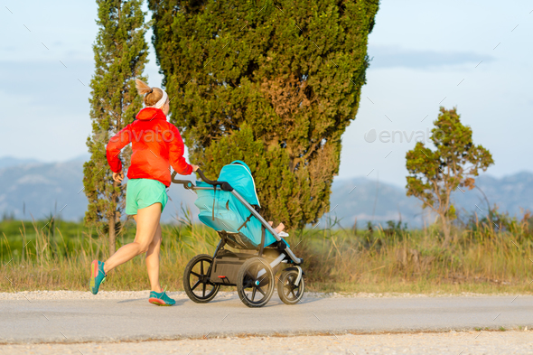 Running mother with stroller enjoying motherhood at sunset lands