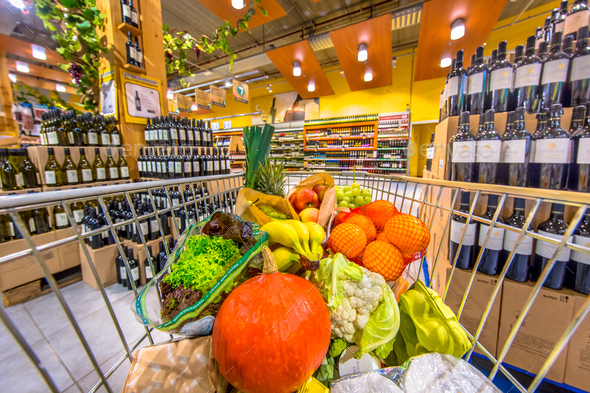 Supermarket trolley with fruit and vegetables on alcohol section