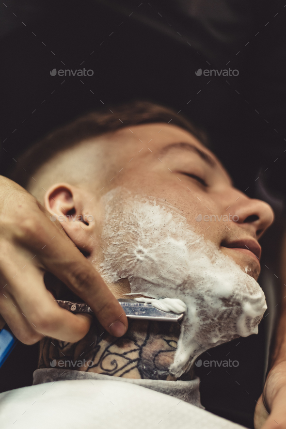 Anonymous man shaving client