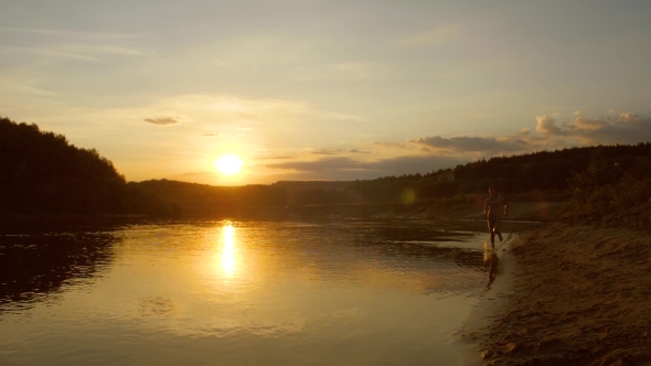 Young Girl Runs Along Beach at Sunset, Splashing Water From Under Her Feet,  Shooting