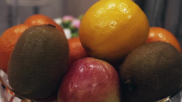 Fresh ripe citrus fruits, apples and kiwi in a plate close-up alt