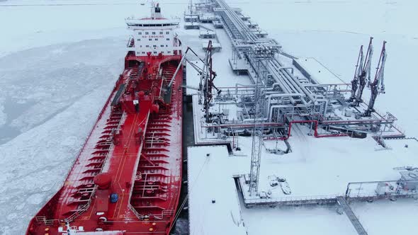 A Large Red Ship Stands at the Pier in the Port and Refuels in Winter alt