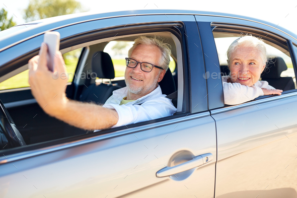 senior couple in car taking smartphone selfie