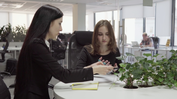 Business Woman Showing Something to Employee on Smartphone During Meeting alt