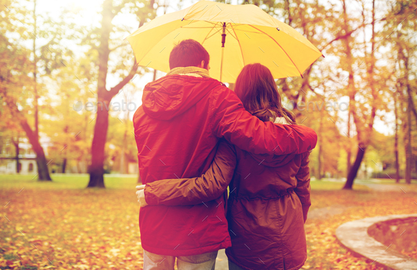 happy couple with umbrella walking in autumn park Stock Photo by dolgachov