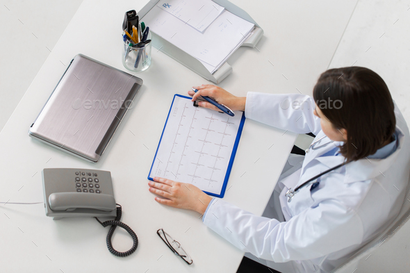 doctor with cardiogram sitting at table - Stock Photo - Images