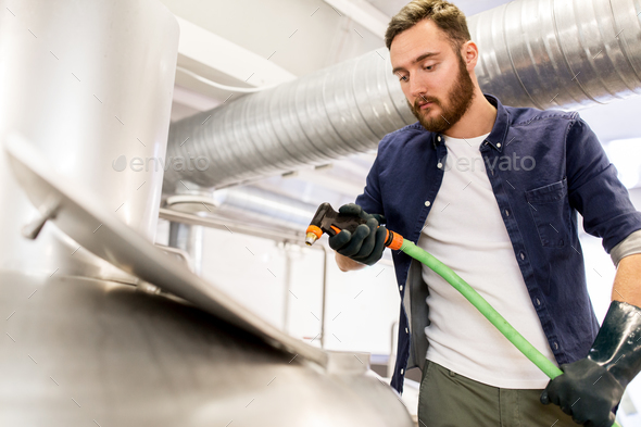 man with hose working at craft beer brewery kettle - Stock Photo - Images