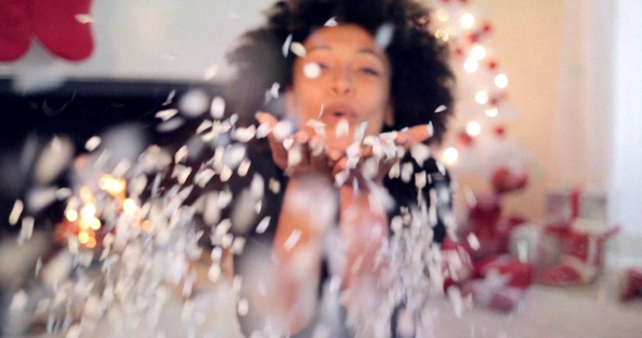 Young Woman Blowing Confetti Off Her Hands alt