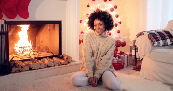 Woman Seated By White Christmas Tree and Presents