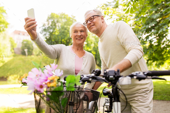 senior couple with bicycles taking selfie at park - Stock Photo - Images