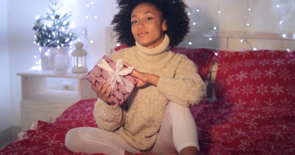 Single Woman Holding Christmas Gift in Bed