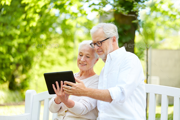 happy senior couple with tablet pc in city park
