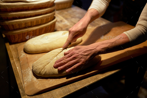 baker making bread and cutting dough at bakery