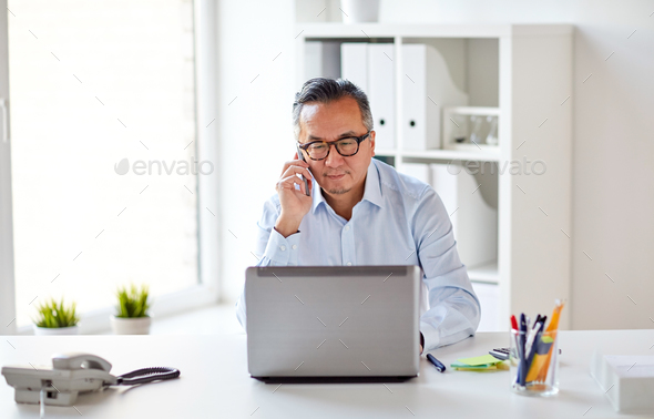 businessman with laptop calling on smartphone