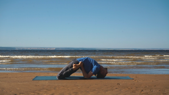 Strong Man Practicing Difficult Yoga Pose on the Beach alt