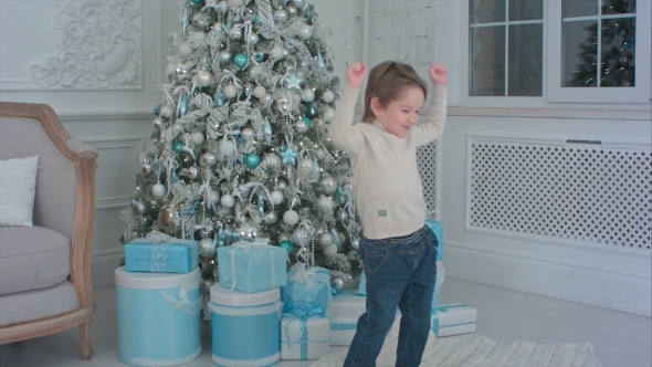 Happy Little Boy Dancing Next To the Christmas Tree and Presents alt