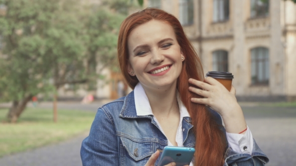 Female Student Laughs at What She See on Her Smartphone on Campus