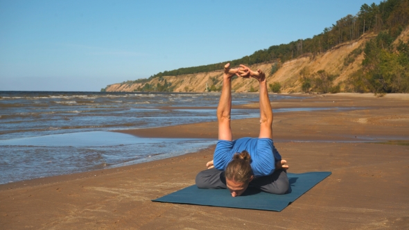 Young Man Doing Thoracic Stretching on a Rock at Sunset Light alt