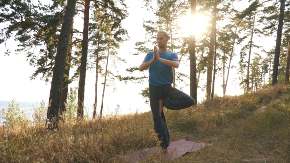 Young Man Doing Yoga in the Woods at Sunset alt