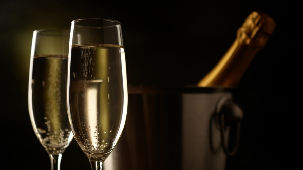 Champagne. Two Flutes with Bottle of Champagne in an Ice Bucket at Background.