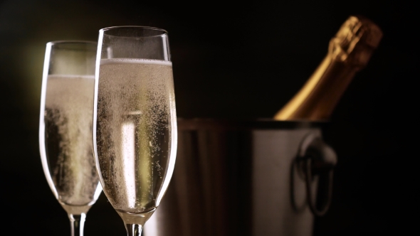 Champagne. Two Flutes with Bottle of Champagne in an Ice Bucket at Background.