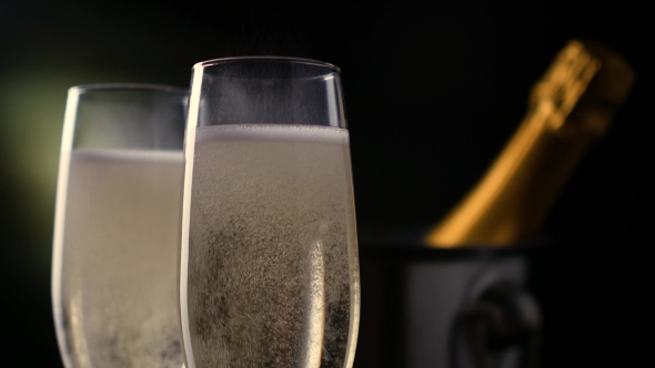 Champagne. Two Flutes with Bottle of Champagne in an Ice Bucket at Background.