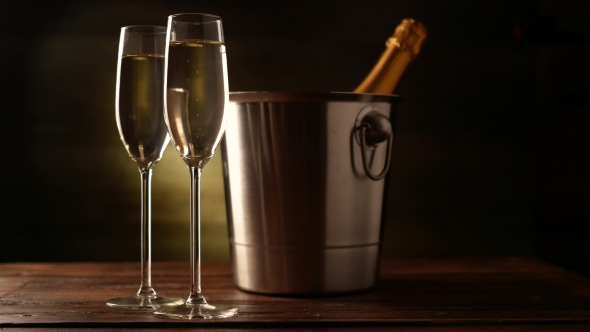 Champagne. Two Flutes with Bottle of Champagne in an Ice Bucket at Background.