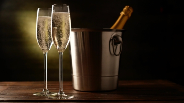 Champagne. Two Flutes with Bottle of Champagne in an Ice Bucket at Background.