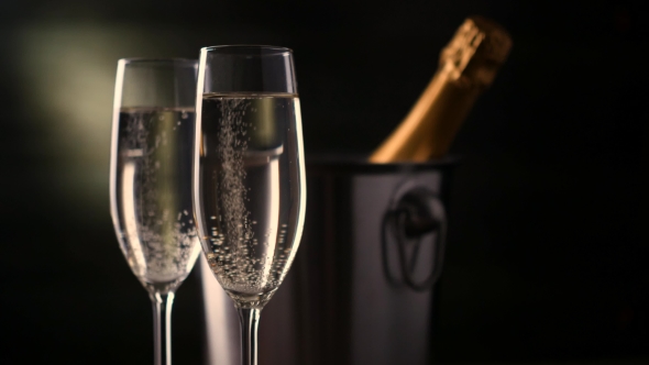 Champagne. Two Flutes with Bottle of Champagne in an Ice Bucket at Background.