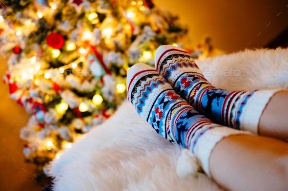 Womans Feet in woollen socks at Christmas tree.